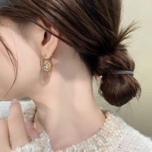 Detail of 18K gold plated zircon earring featuring a spiral design worn by a model