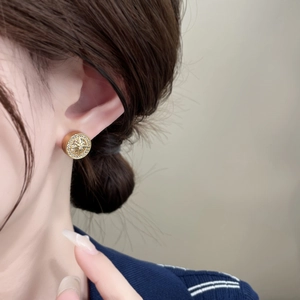 Close-up of elegant gold starburst stud earrings with micro-inlaid zircon on a model