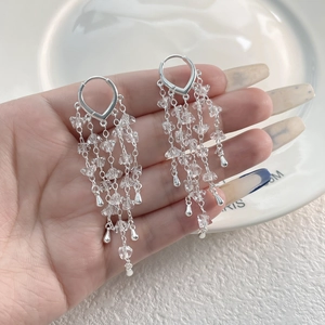 Detail of long fringe earrings with sparkling crystals and 18K gold plated metal tassels