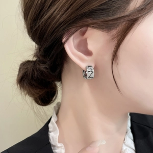 Macro view of wide silver earrings with micro-paved black stones in FF logo pattern