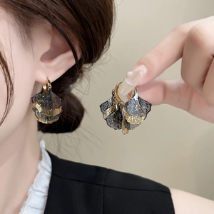 Vintage layered ginkgo leaf earrings in black and gold finish shown on model