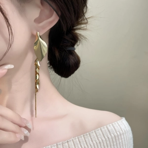 Detail of vintage gold leaf tassel earrings with long chain fringe on a female model