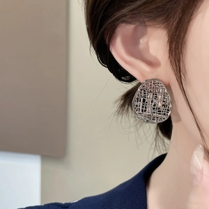 Detail view of silver mesh earrings with white cubic zirconia on model's ear