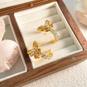 Detailed macro view of gold bow-shaped earrings with pearls in a luxury jewelry box