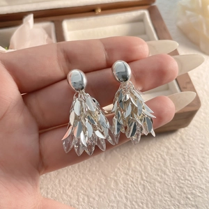 Vue détaillée de boucles d'oreilles à pompons argentés avec feuilles et cristaux