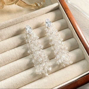 Macro shot of silver diamond-shaped long tassel earrings with clear faceted crystal beads