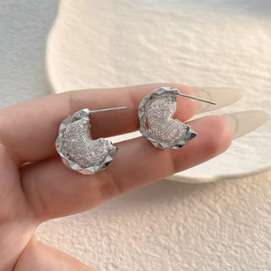 Close-up of S925 sterling silver earrings with textured crescent design and engraved hallmark
