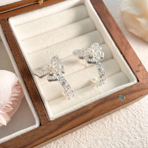 Detail of silver bow earrings with pearls and zircons in a velvet gift box
