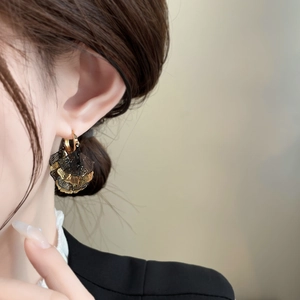 Vintage wing-shaped layered earrings in black and gold finish worn by a female model