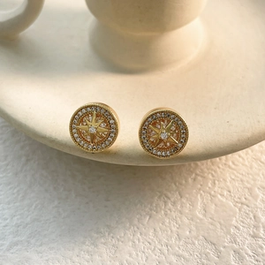Macro shot of gold starburst stud earrings with micro-set cubic zirconia on ceramic base