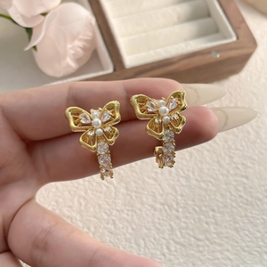 Elegant gold double butterfly earrings with pearls and crystal droplets on floral background