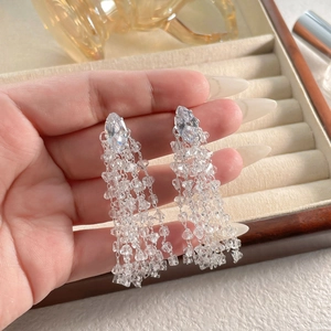 Macro detail of silver tassel drop earrings featuring marquise-cut zircon and fine beads