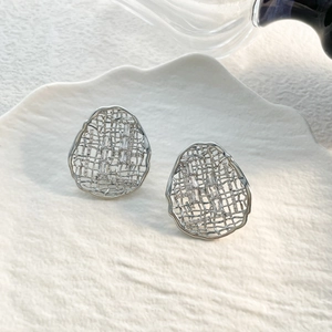 Detail shot of silver plated grid oval earrings with sparkling cubic zirconia on a ceramic dish