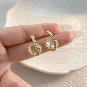 Luxury 18K gold plated sunflower zircon stud earrings held by hand over a cream tray