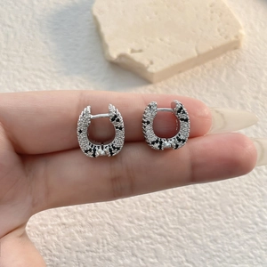 Detail of luxury U-shaped earrings with leopard print pavé zircons on silver metal