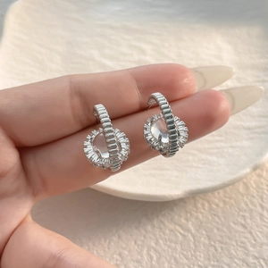 Macro shot of silver geometric zircon earrings with radial texture on fingers