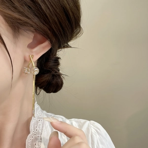 Pendientes largos dorados con borlas y bolas de cristal brillantes en una modelo