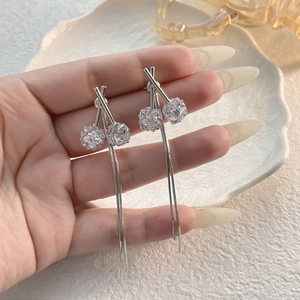 Detalle de pendientes de trébol plateados con circones brillantes y borlas largas