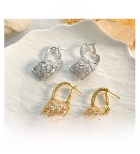 Macro view of gold and silver padlock earrings set with sparkling rectangular zircons