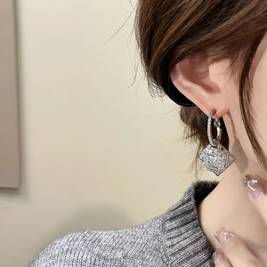 Close-up of geometric diamond earrings in a rhodium finish on a model showing sparkle