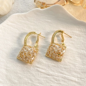Close-up of geometric square drop earrings with 18K gold plating and cubic zirconia