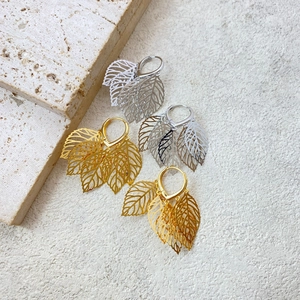 Detailed view of gold and silver hollow leaf pendant earrings with natural vein textures