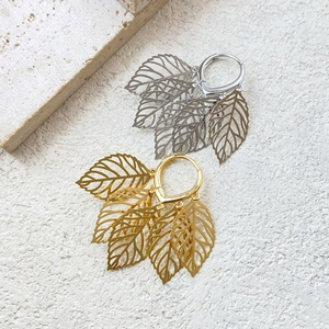 Minimalist leaf pendant drop earrings in gold and silver finish on stone background