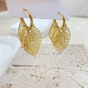 Elegant 18K gold leaf drop earrings with intricate hollow veins on a textured surface