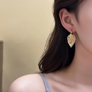 Elegant gold hollow leaf drop earrings featuring detailed bionic veins on female model