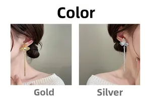 Dettaglio di orecchini a fiore oro e argento con nappine indossati da una modella