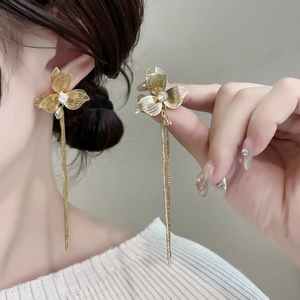 Eleganti orecchini a nappa con fiori dorati e cristalli su modella per stile di lusso