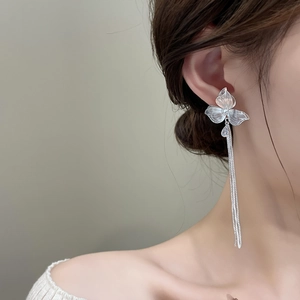 Dettaglio di orecchini a fiore d'argento con nappe e zircone su una modella
