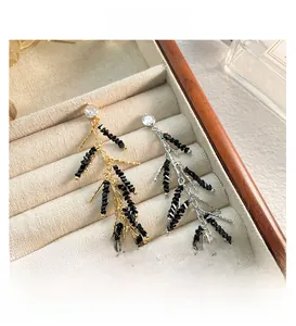 Macro shot of long black beaded tassel earrings with gold and silver accents