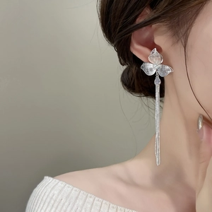 Eleganti orecchini a fiore d'argento con nappe e cristalli su una modella in profilo