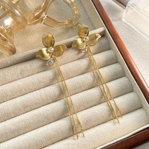 Dettaglio di orecchini a fiore dorato con nappe e zirconi in un porta gioielli