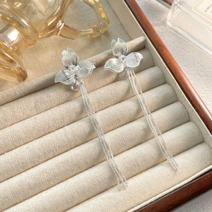 Dettaglio macro di orecchini a fiore in argento con lunghe nappe e diamanti lucidi