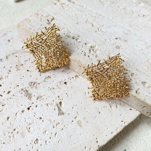 Modern gold square stud earrings featuring a unique woven mesh texture on a stone plate