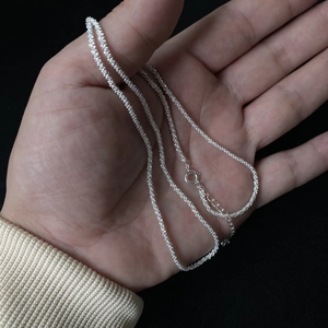 Macro detail of silver-toned textured chain with spring clasp and adjustable length extension