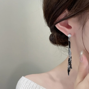 Detail of long fringe earrings with cubic zirconia stud and black beaded silver chains