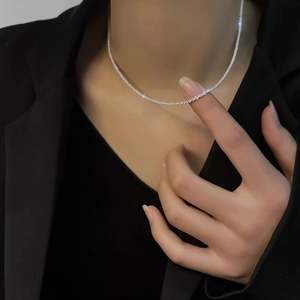 Minimalist sparkling silver choker necklace worn by a model in a black suit for elegant style