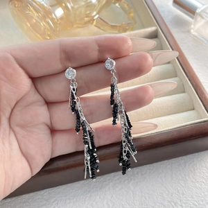 Detail of elegant silver tassel earrings featuring black faceted beads and a clear gemstone
