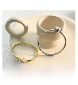 Macro shot of minimalist gold and silver hoop earrings with heart-shaped zircon charms
