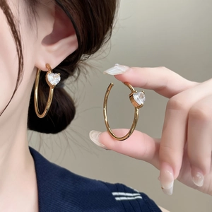 Elegant gold hoop earrings with sparkling heart zircon stone shown on model profile