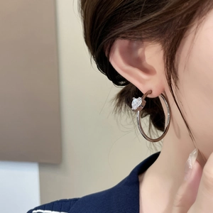 Detail of silver hoop earring featuring a sparkling heart-shaped cubic zirconia stone