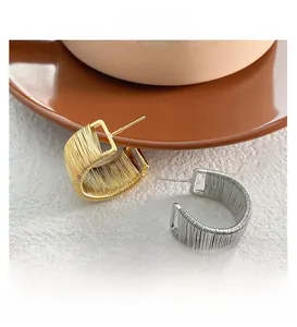 Detailed view of woven metal rectangular earrings with gold and silver wire wrapping