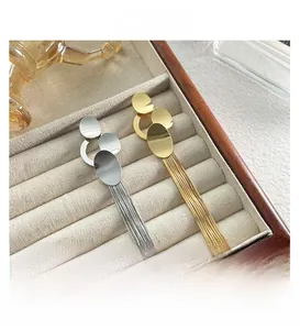 Detailed close-up of long tassel earrings in gold and silver finish on velvet display