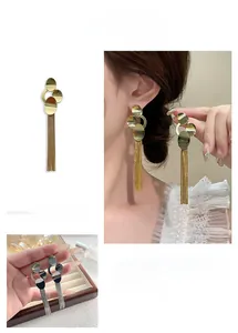 Detail view of long tassel fringe earrings with metallic discs in gold and silver plating
