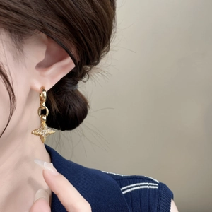 Macro detail of gold star earrings with micro-set zircons on a female model