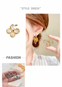 Detailed view of layered hollow flower earrings in gold and silver finish on model ear