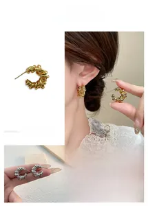 Detailed shot of twisted rope knot hoop earrings in polished gold and silver finishes